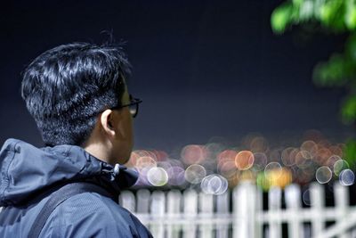 Rear view of man wearing sunglasses against sky at night