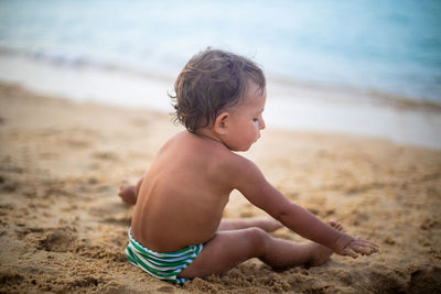 Boy sitting on sand at beach