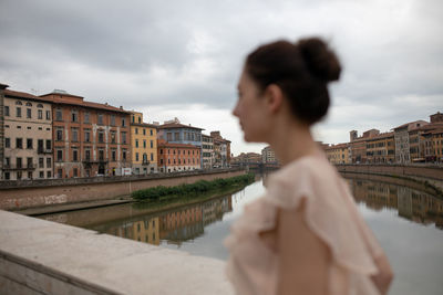 Side view of woman standing against river in city
