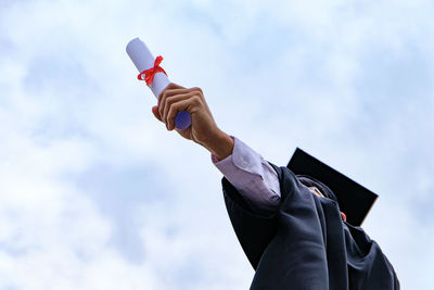 Low angle view of man holding umbrella against sky