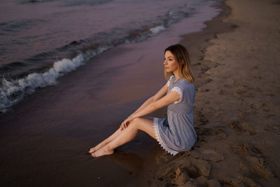 Woman sitting on sand at beach