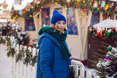 Woman in blue jacket and green scarf and white gloves in winter. square in moscow on christmas day