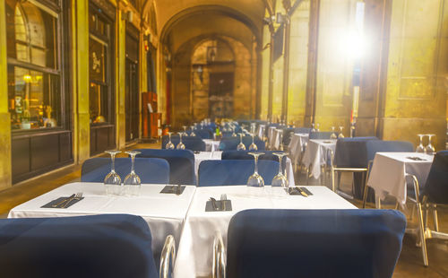 Empty summer street cafe with covered white tables on sunlight