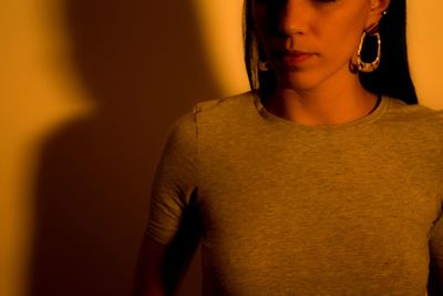 Close-up of young woman standing against wall at home