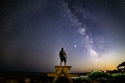 Low angle view of man standing against sky at night