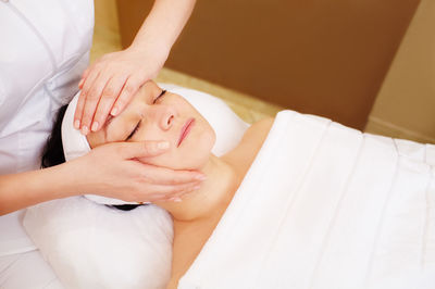 High angle view of woman receiving facial massage in spa
