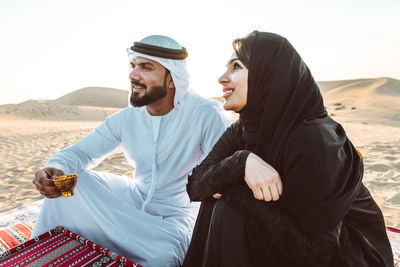 Arabian couple sitting at desert