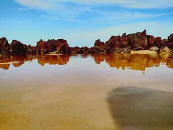 Scenic view of river and rocks against blue sky