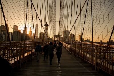 People walking on footbridge in city against sky