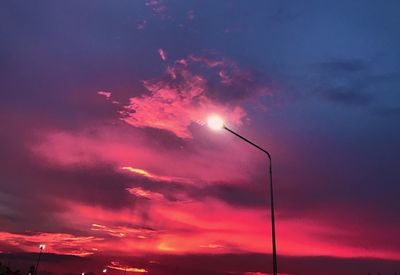 Low angle view of illuminated street lights against dramatic sky