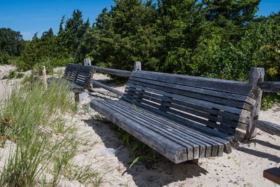 Empty bench in park against sky