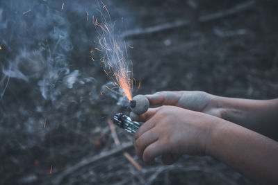 Cropped hands burning firework over field