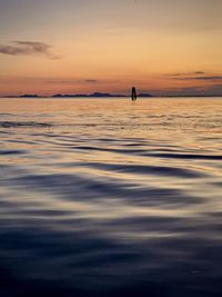 Silhouette person in sea against sky during sunset