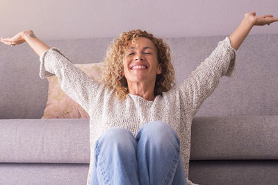 Portrait of young woman sitting on sofa at home