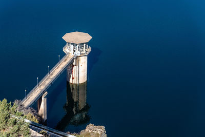 High angle view of lighthouse by sea against clear sky