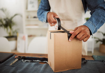 Midsection of man opening cardboard box