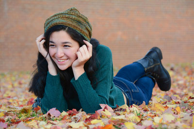 Smiling woman lying on field during autumn at park