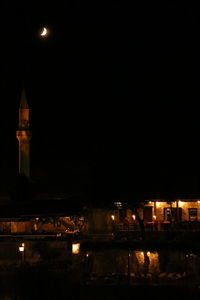 Illuminated buildings against clear sky at night