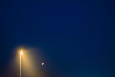 Low angle view of illuminated street light against clear blue sky