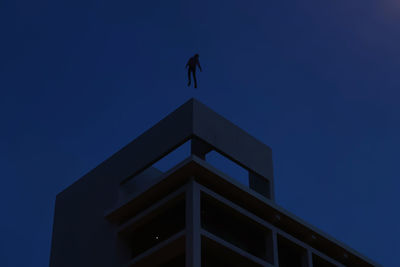 Low angle view of silhouette building against clear blue sky