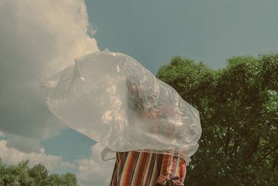 Man wearing plastic bag against sky