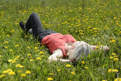 Full length of woman lying on grass by flowering plants