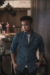 Young man looking away while standing at cafe