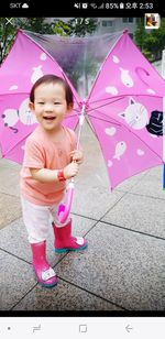 Portrait of cute girl playing with pink umbrella