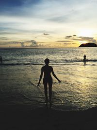 Silhouette men standing on beach against sky during sunset