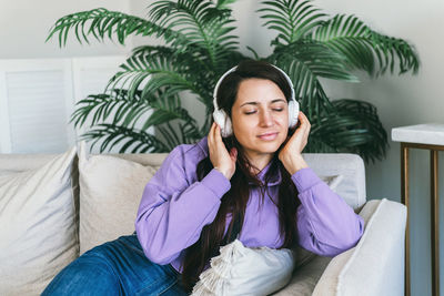 A woman in headphones listens to her favorite music at home on the couch.