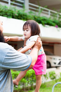 Midsection of father carrying daughter outdoors