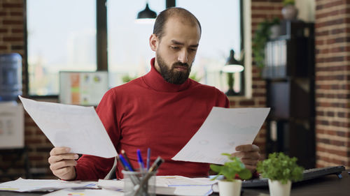 Businessman analyzing documents at desk in office