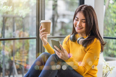 Young woman holding coffee while sitting at home