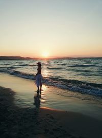 Full length of woman on beach against sky during sunset