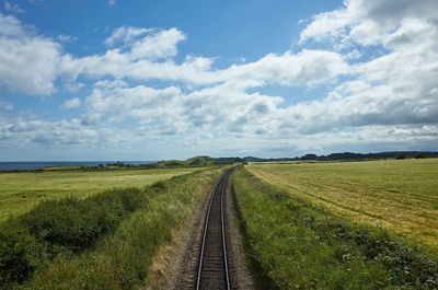 Railroad tracks on field against sky