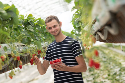 Portrait of young woman standing against plants