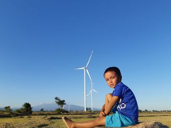 Boy standing on land against clear blue sky