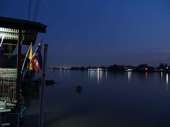 Scenic view of lake against buildings at night