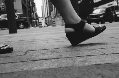 Low section of woman walking on sidewalk in city