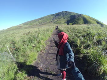 Rear view of man walking on mountain against sky