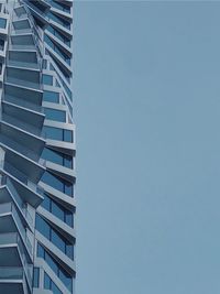 Low angle view of modern, spiraling building against clear blue sky. 