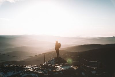 Rear view of man standing on mountain against sky