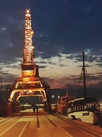 Illuminated tower against sky during sunset in city