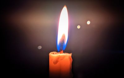 Close-up of burning candle against black background