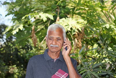 Portrait of man holding mobile phone outdoors