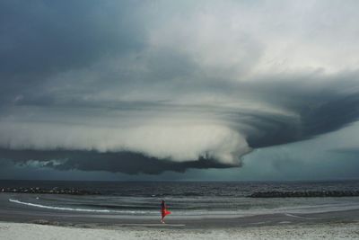 Woman standing on shore during stormy weather