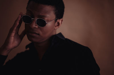 Portrait of young man wearing sunglasses against wall