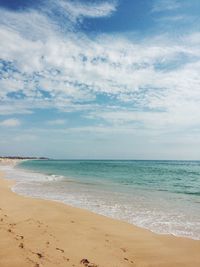 Scenic view of beach against cloudy sky
