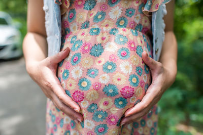 Midsection of woman touching abdomen while standing on street