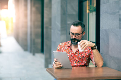 Man using digital tablet while sitting at table